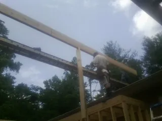 Carpenter setting a ridge beam over a new addition frame — Ice Dam Removal by Roofing Brothers in Stanwood